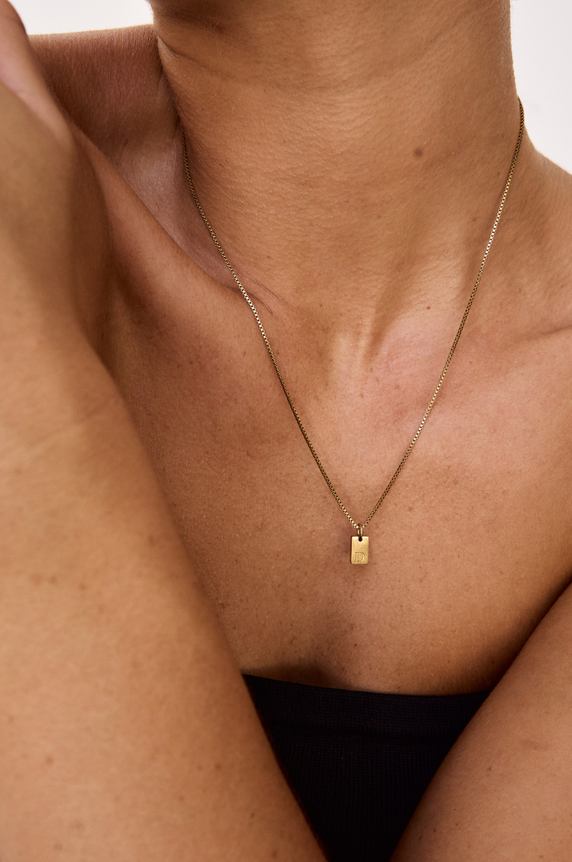 Close up of model wearing a gold initial letter pendant necklace from australian online store Martini Street which sells waterproof, high quality jewellery.